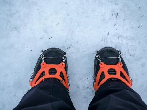 Two legs in winter boot with ice snow grips. Snow traction cleats. Stock Photos