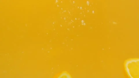 Two lemon slices fall into the water on a yellow background. Fruit under water Stock Footage 154708937
