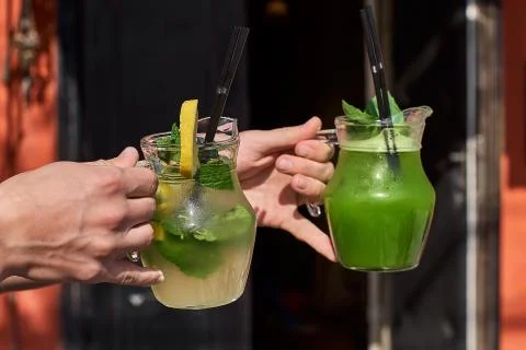 Two lemonade in the hands of the man. fresh cucumber and lemon drinks. Stock Photos