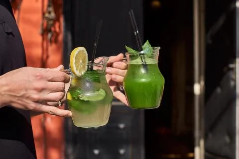 Two lemonade in the hands of the man. fresh cucumber and lemon drinks. Stock Photos