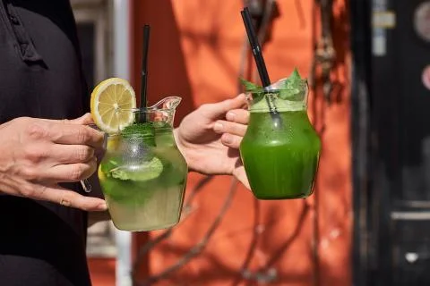 Two lemonade in the hands of the man. fresh cucumber and lemon drinks. Stock Photos