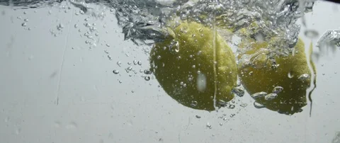 A two lemons falls into the water producing large splashes. Stock Footage 106007922
