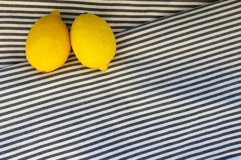 Two lemons on striped textile background. Frame, top view. Free space Stock Photos