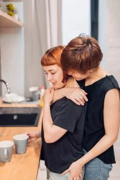 Two lesbians are embracing in the kitchen Stock Photos