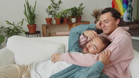 Two lgbt men are lying on the sofa, looking at each other and stroking hair Stock Footage 174452239