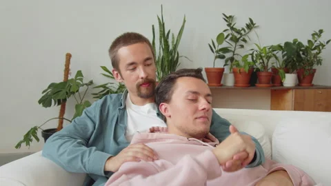 Two lgbt men are sitting together on the sofa in the living room, talking and Stock Footage 174463409