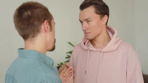 Two lgbt men are standing together in the living room, talking to each other and Stock Footage 173792534