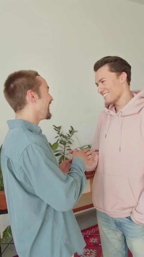Two lgbt men are standing together in the living room, talking to each other and Stock Footage 173907141