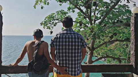 Two lgbt stand side by side, in the middle of nature and the blue sea. Stock Photos