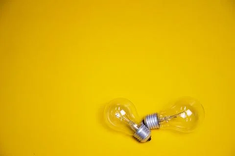 Two light bulbs placed on a yellow background Foto stock