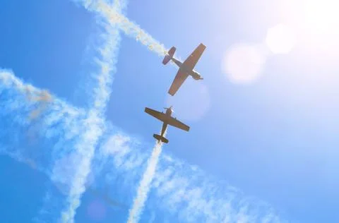Two light engine aircraft with a trace of white smoke fly in the blue sky. Stock Photos