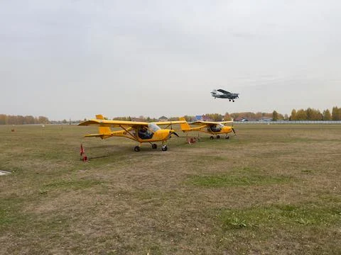 Two light yellow light-engine airplanes on the background of a flying plane. Stock Photos