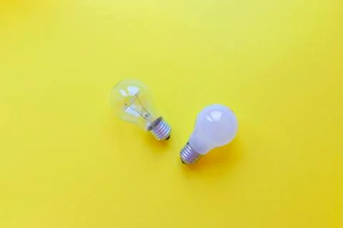 Two lightbulbs on yellow background. Transparent bulb and white bulb with Stock Photos