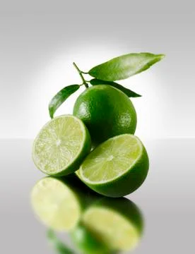 Two lime halves in front of a whole lime Stock Photos