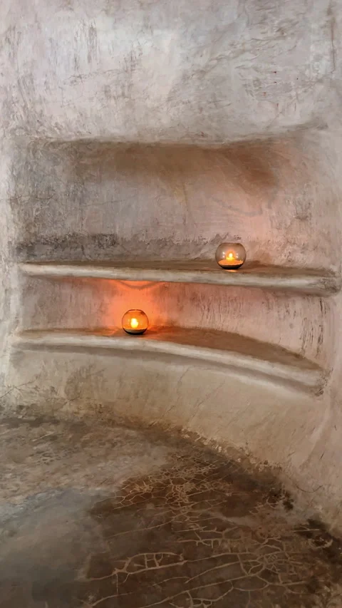 Two lit candles on the shelves created in the alcove. Wall carved in the stone. Stock Footage 327734570