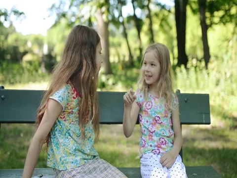Two little beautiful sisters play on wooden bench Stock Footage 83733045