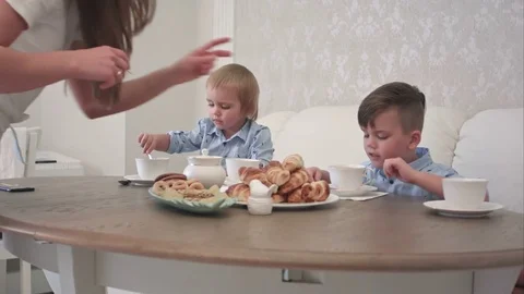 Two little boys drinking tea with pastry at the table Видео 76582621