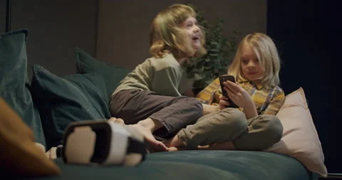 Two little boys using smartphone playing virtual reality at home, funny brothers Stock Footage 154385417