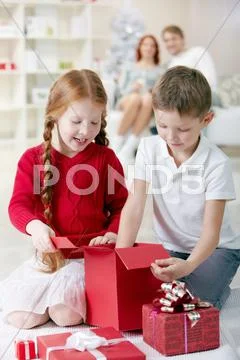 Two little children examining Christmas gift boxes at home Stock Photos