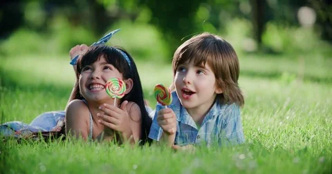 Two little children with a Lollipop,Caucasian boy and Asian girl having fun Stock Footage