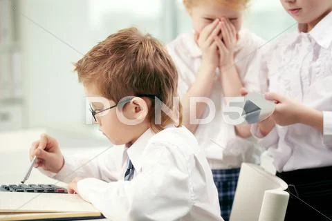 Two little girls going to put a huge thumbtack on boy's chair Stock Photos