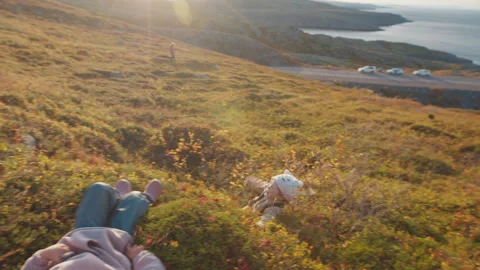 Two little girls rolling down a hill. Russia, Teriberka Stock Footage 301627706
