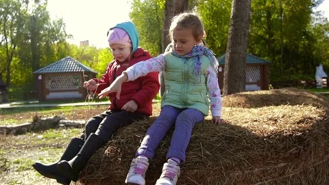 Two little girls sitting on a haystack and throwing hay down Видео 70825389