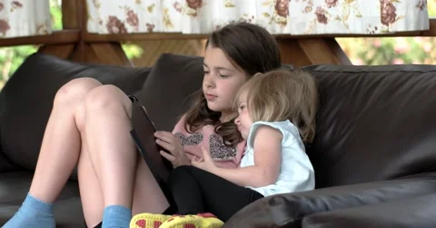 Two Little Girls Using Tablet Computer on Sofa on Terrace Vídeo Stock 65195630
