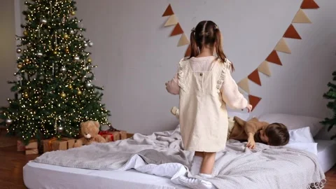 Two little sibling children having fun at home, jumping on a bed on Christmas Stock Footage 314066014