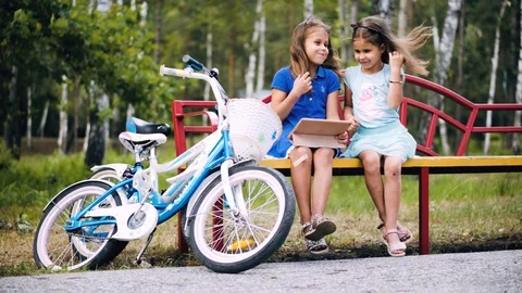 Two little sisters play in the tablet outdoors Stock Footage 113208853