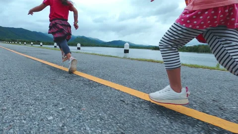 Two little sisters running forward along the lakeside road at sunset. Childhood  Stock Footage 163648909