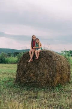 Two little sisters sit on a haystack Stock Photos