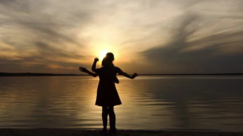 Two little sisters wave their hands in front of the setting sun and a large l Vídeos de archivo 200448571