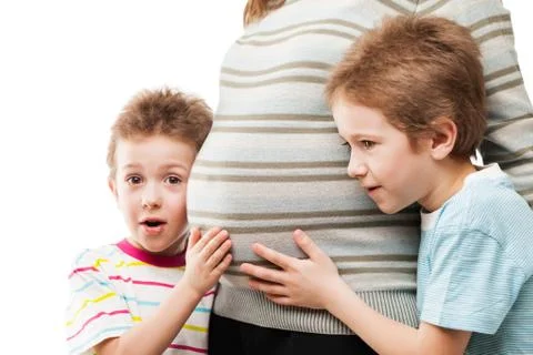 Two little sons touching or bonding their pregnant mother abdomen Stock Photos