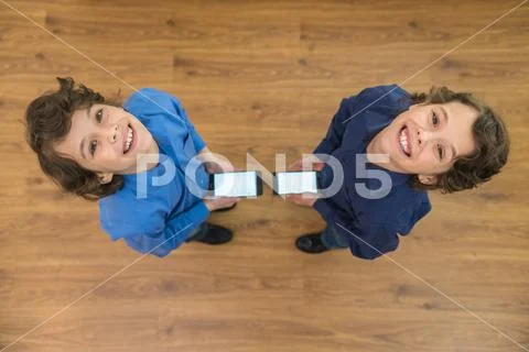 The two little twin stand with a phone. View from above Stock Photos