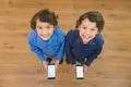 The two little twin stand with a phone. View from above Photo