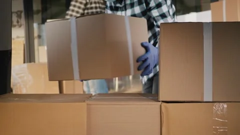 Two loaders in checkered shirts move cardboard boxes into a delivery van du.. Stock Footage 334607683
