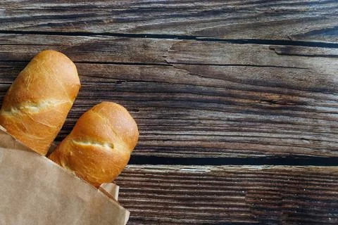 Two loaf of handmade baguette Bread packed in paper on wooden table. Close up Stock Photos