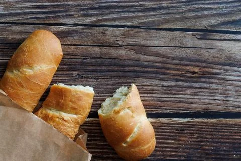 Two loaf of handmade baguette Bread packed in paper, whole and broken offf piece Stock Photos