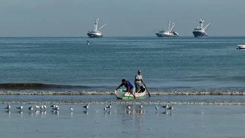 Two local fishermen pull the boat ashore in Manta, Ecuador Stock Footage 88814828