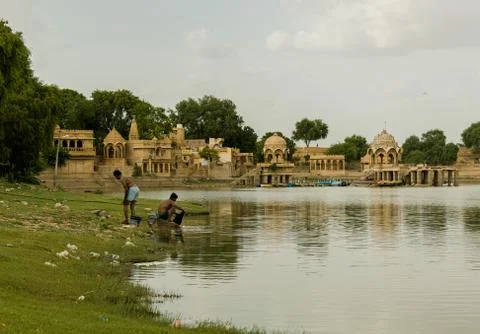 Two local men bathing and washing clothes in lake at sunset Stock Photos