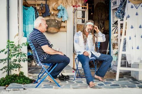 Two local men sitting outside shop in Mochlos village, Crete, Greece Stock Photos