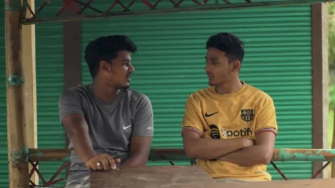 Two local young men are sitting at a tea stall and chatting Stock Footage 296526151