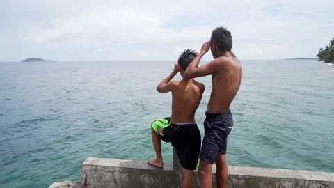 Two locals standing on pier and watching the ocean Video stock 231753758