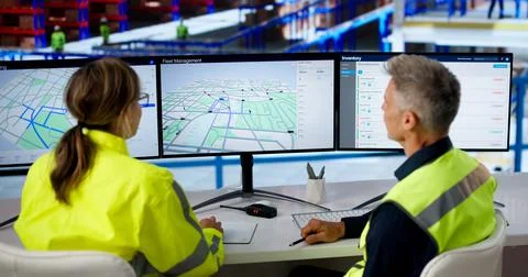 Two Logistics Coordinators Use Computer Screens To Track Delivery Routes Effi 库存照片