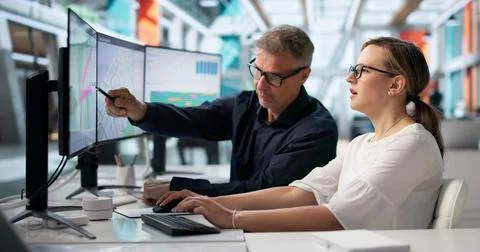 Two Logistics Coordinators Use Multiple Computer Screens To Track Delivery Fl Stock Photos