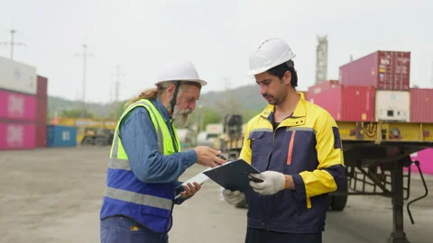 Two logistics workers discuss a shipping manifest on a clipboard in a container Stock Footage 342280772