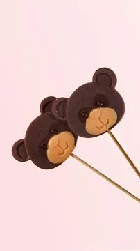 Two lollipops in the shape of a bear's face on a pink background. Sweet love. Stock Photos