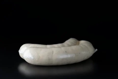 Two long white raw bratwurst sausage in plastic wrap on black background Stock Photos