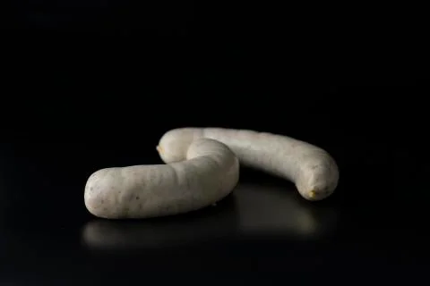 Two long white raw bratwurst sausage isolated on black background Stock Photos